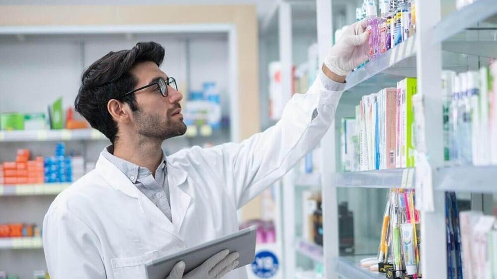 یک داروساز در حال برداشتن دارو از قفسه
